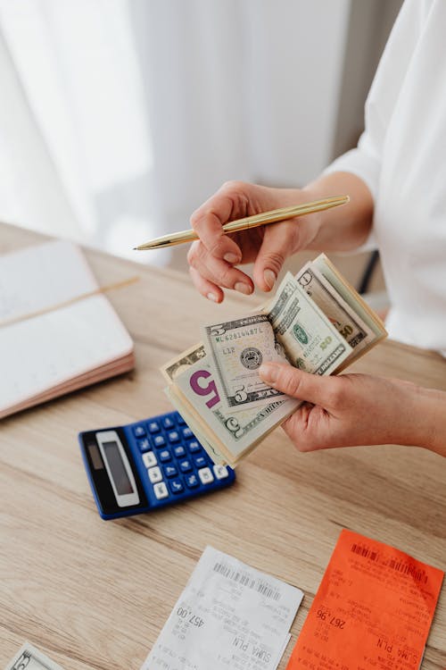 Woman planning advertising budget with calculator and cash at her desk