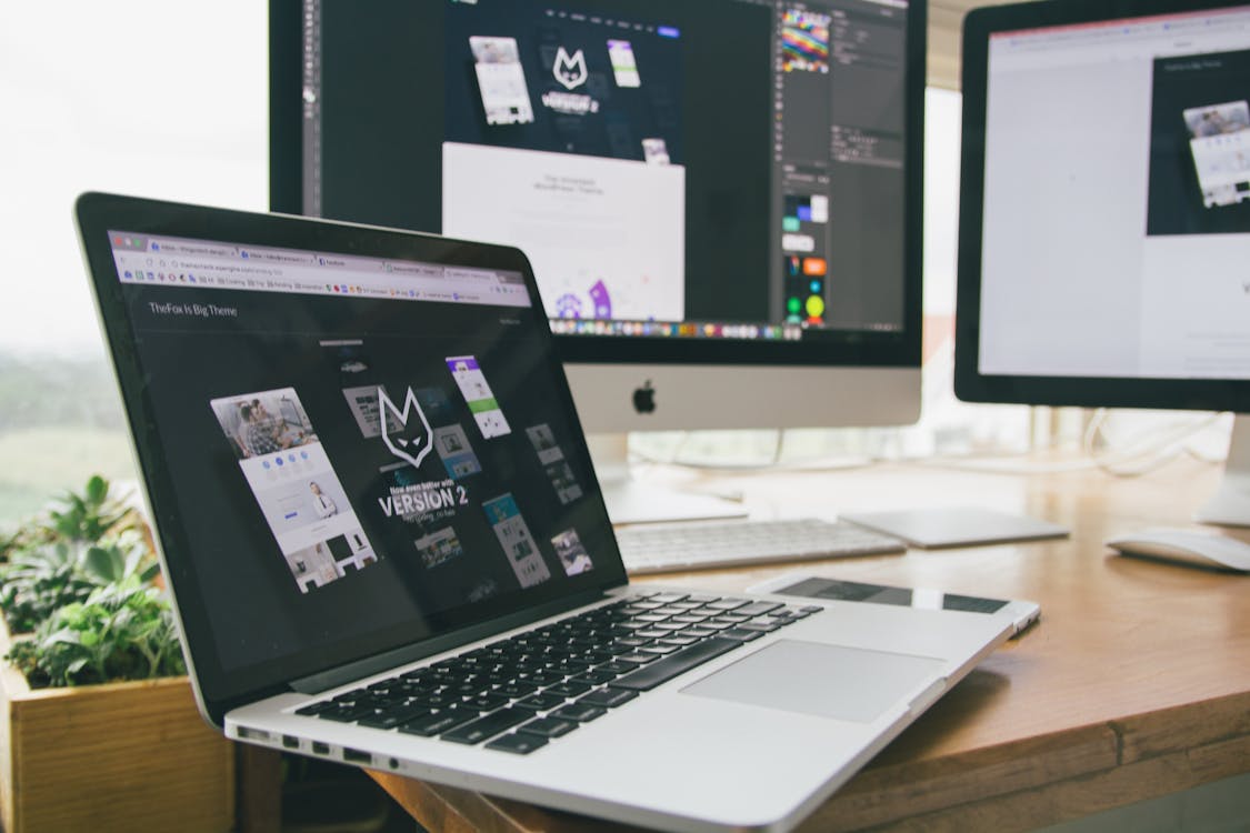 Stylish workspace with a laptop and monitors displaying design software