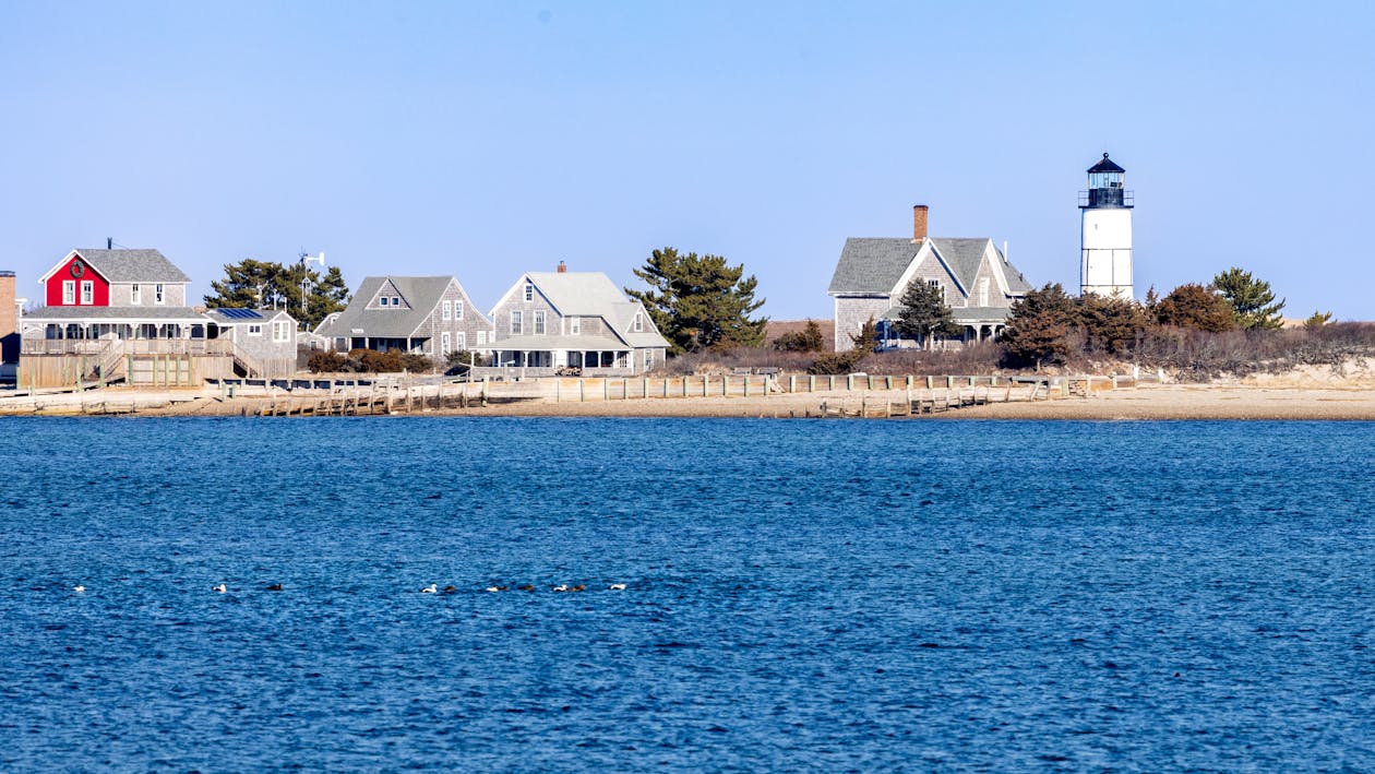 Cape Cod lighthouse by the shoreline under clear blue skies