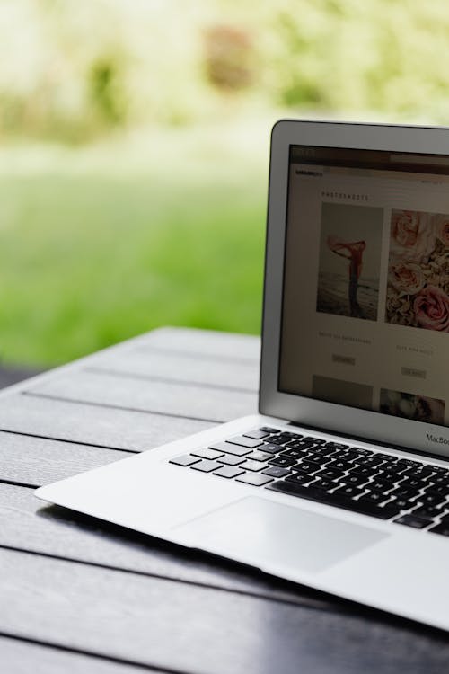 Open laptop on a table displaying a website in an outdoor setting